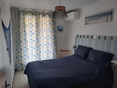 a bedroom with a blue bed and a window at Les sables d'or in Port-la-Nouvelle