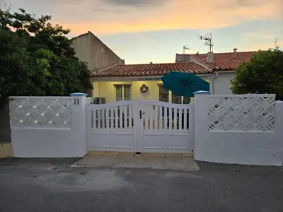 a white fence with an umbrella in front of a house at Les sables d'or in Port-la-Nouvelle