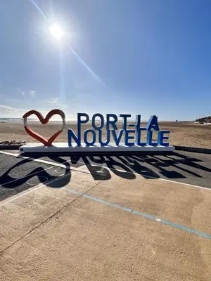 a bench with a sign in a parking lot at Les sables d'or in Port-la-Nouvelle