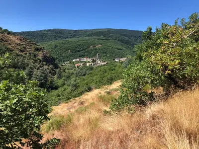 a view of a hill with a village in the distance at Maison de campagne Les loirs in Lespinassière