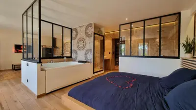 a bedroom with a large bed and a bath tub at Le Relais de Diligence Balnéo & Sauna in Salsigne