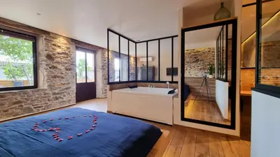 a bathroom with a large tub and a large bed at Le Relais de Diligence Balnéo & Sauna in Salsigne