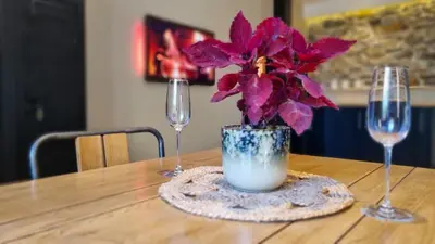 two wine glasses and a vase with flowers on a table at Le Relais de Diligence Balnéo & Sauna in Salsigne