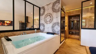 a large bath tub in a room with a fireplace at Le Relais de Diligence Balnéo & Sauna in Salsigne