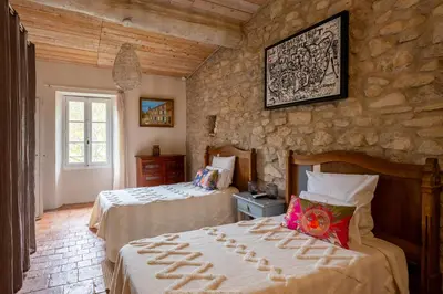 a bedroom with two beds and a stone wall at Prieuré Saint-Louis Maison d'Hôtes in Floure