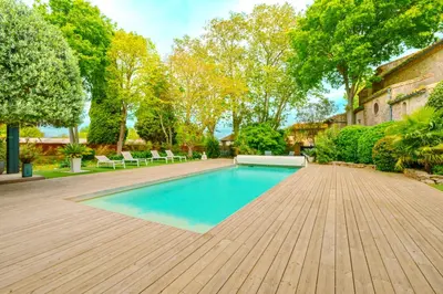 a swimming pool in a yard with a wooden deck at Prieuré Saint-Louis Maison d'Hôtes in Floure