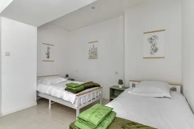 two beds in a room with white walls and green towels at L'Alchémille Terrasse Wifi in Peyriac-de-Mer