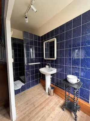 a blue tiled bathroom with a sink and a mirror at Demeure Familiale du 19ème Siècle in Bram