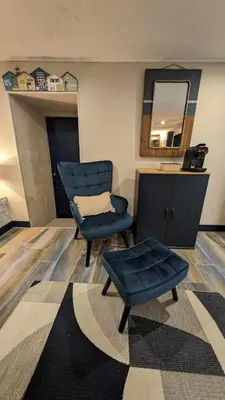 a living room with a chair and a mirror at Studio 35m², Terrasse & Cuisine proche Carcassonne in Montclar