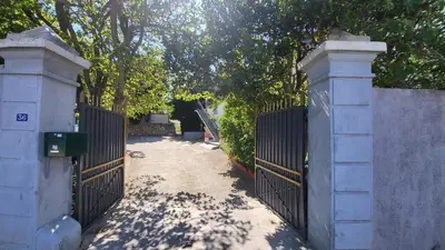 a gate to a driveway with trees in the background at Bel Appartement in Vinassan
