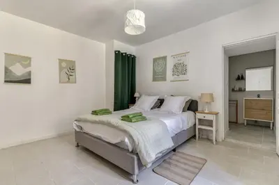 a bedroom with a large bed with a green curtain at Le Cyperus Appartement avec Terrasse et Wifi in Peyriac-de-Mer