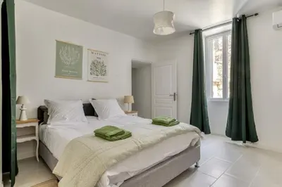 a bedroom with a large bed with green curtains at Le Cyperus Appartement avec Terrasse et Wifi in Peyriac-de-Mer