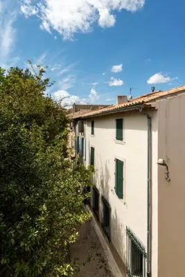 an alley way between two buildings with trees at Le Dichondra Wifi Proche des Pontons in Peyriac-de-Mer
