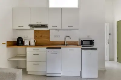 a white kitchen with a sink and a microwave at Le Dichondra Wifi Proche des Pontons in Peyriac-de-Mer