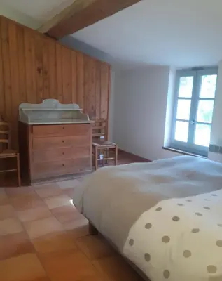 a bedroom with a bed and a dresser and a window at Le Pigeonnier au dessus du lac in Caraman