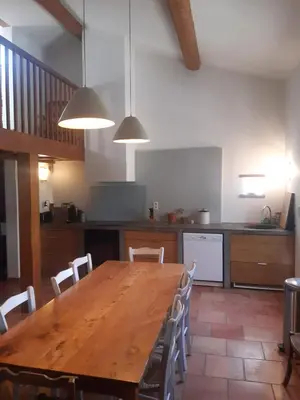 a kitchen with a wooden table and chairs at Le Pigeonnier au dessus du lac in Caraman