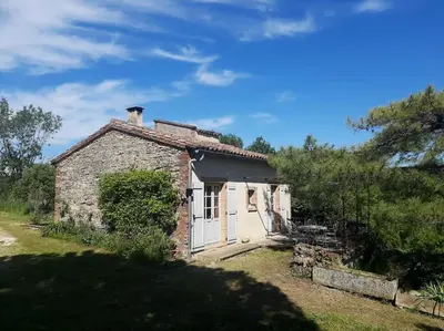 an old stone house with a white door at Le Pigeonnier au dessus du lac in Caraman