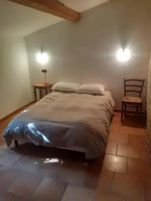 a bedroom with a large bed and a chair at Le Pigeonnier au dessus du lac in Caraman