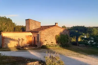 an old brick house sitting in the middle of a field at Le Pigeonnier au dessus du lac in Caraman