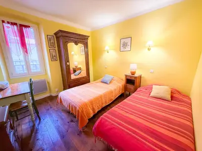 a bedroom with two beds and a desk and a window at La Maison Bleue, nid chaleureux en bord de rivière in Rennes-les-Bains