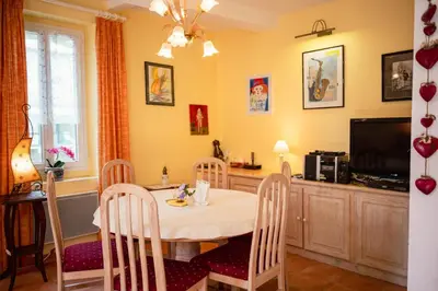 a dining room with a table and chairs and a television at La Maison Bleue, nid chaleureux en bord de rivière in Rennes-les-Bains
