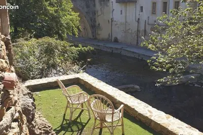 two chairs sitting on the grass next to a stream at La Maison Bleue, nid chaleureux en bord de rivière in Rennes-les-Bains
