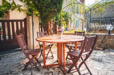 a wooden table and chairs with a candle on it at La Maison Bleue, nid chaleureux en bord de rivière in Rennes-les-Bains