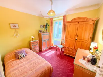 a bedroom with a bed and a cabinet and a window at La Maison Bleue, nid chaleureux en bord de rivière in Rennes-les-Bains