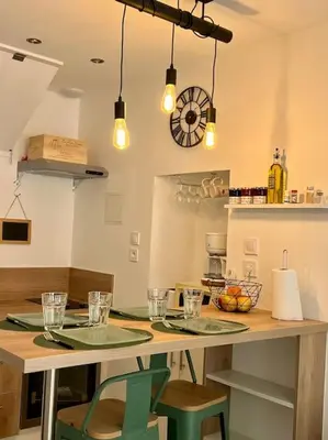 a kitchen with a table with two chairs and lights at Charmante maison de village in Peyriac-de-Mer