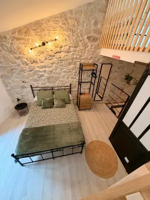 a bedroom with a bed and a stone wall at Charmante maison de village in Peyriac-de-Mer