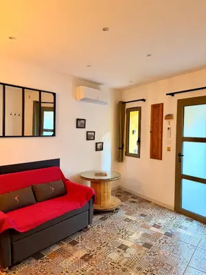 a living room with a red couch and a table at Charmante maison de village in Peyriac-de-Mer