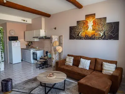 a living room with a couch and a kitchen at Maison Chevalier in Narbonne