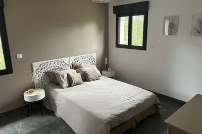 a bedroom with a bed with white sheets and a window at Jolie villa avec piscine in Palaja