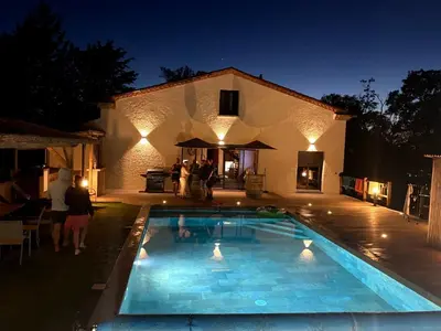 a swimming pool in front of a house at night at Jolie villa avec piscine in Palaja