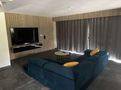 a living room with a blue couch and a tv at Jolie villa avec piscine in Palaja