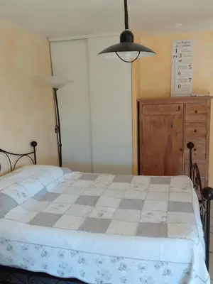 a bedroom with a bed and a dresser and a lamp at Gite de l'Etang proche des Grands Buffets in Narbonne