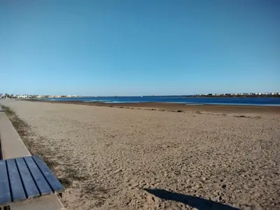 a bench sitting on a beach next to the water at Très beau Studio Cosy à 500m de la Plage in Gruissan