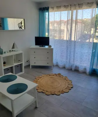 a living room with a table and a rug at Très beau Studio Cosy à 500m de la Plage in Gruissan