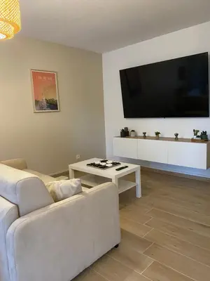 a living room with a white couch and a flat screen tv at Appartement Carcassonne résidence capucins in Carcassonne