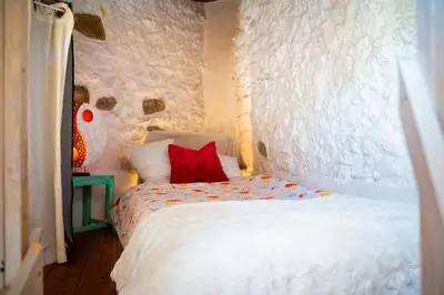 a bedroom with a white bed with a red pillow at Petite Maison de Resource avec Cuisine in Rennes-les-Bains