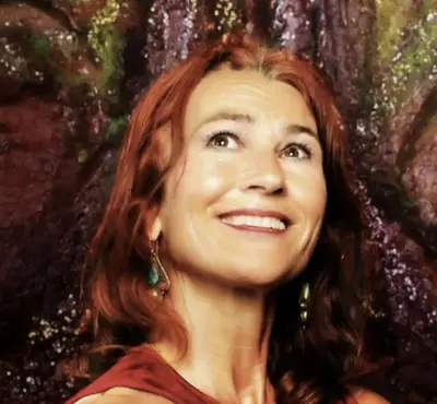 a woman with red hair standing in front of a tree at Petite Maison de Resource avec Cuisine in Rennes-les-Bains