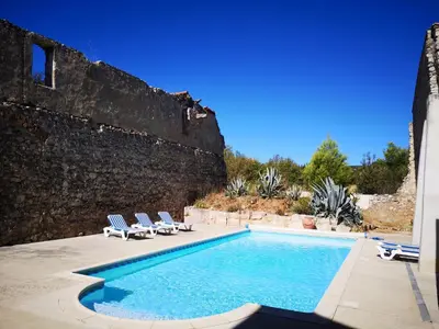 a swimming pool with two lounge chairs and a wall at Domaine de La Pierre Chaude in Portel-des-Corbières