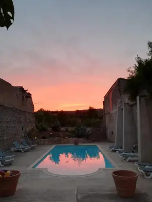 a swimming pool with a sunset in the background at Domaine de La Pierre Chaude in Portel-des-Corbières