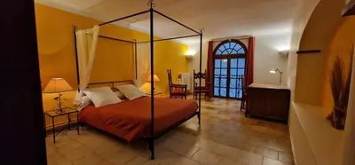 a bedroom with a canopy bed and a table at Domaine de La Pierre Chaude in Portel-des-Corbières