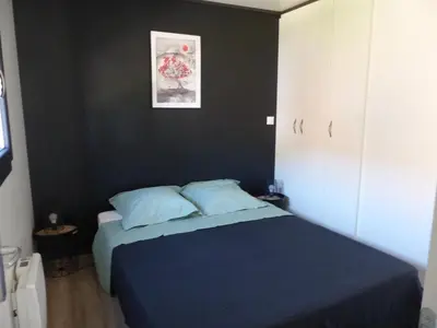 a bedroom with a blue bed and a black wall at Cottage du Lac in Olonzac