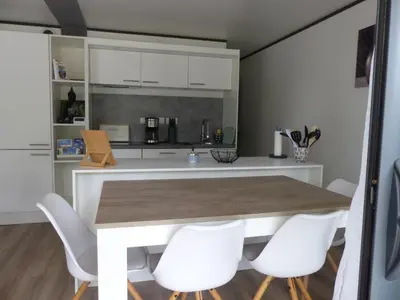 a kitchen with a wooden table and white chairs at Cottage du Lac in Olonzac