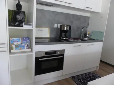 a small kitchen with white cabinets and a stove at Cottage du Lac in Olonzac