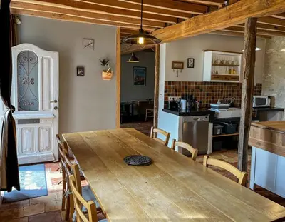 a dining room with a wooden table and a kitchen at Domaine du Léou in Fiac