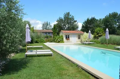 a swimming pool in a yard with umbrellas at Domaine du Léou in Fiac