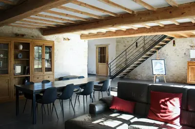 a living room with a table and chairs and a staircase at Domaine du Léou in Fiac